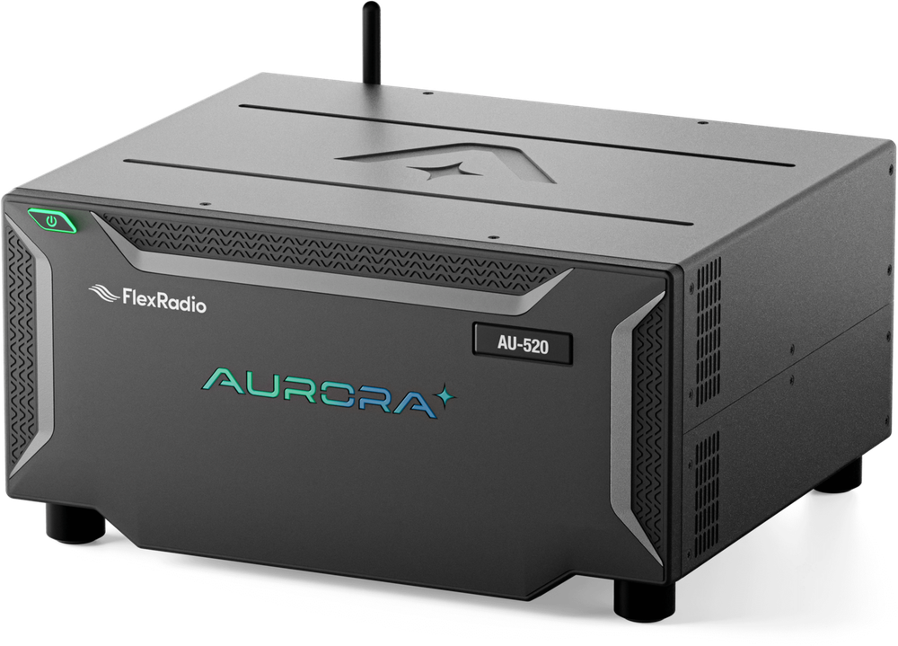 A FlexRadio Aurora — a low, dark, finned desktop transceiver chassis
                with a small antenna on top and a green power button.
